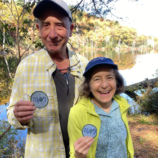 Close-up of Tim and Di each holding some sort of mysterious patch that I do not understand, both smiling.