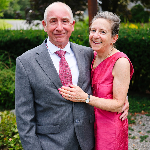 Tim in a gray suit and Di in pink, posed for a portrait and smiling.