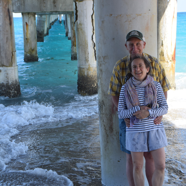 Tim and Di under a florida Pier in warm sunlight, both smiling at the camera.